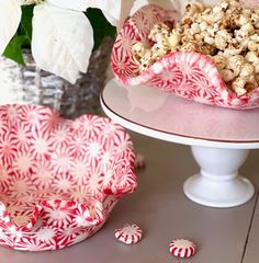 two plates with candy canes on them next to a flower pot and bowl full of popcorn