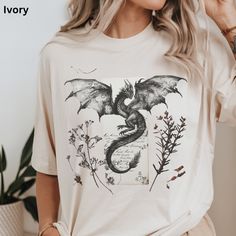 Romantasy Reader Dragon T-Shirt Pressed Wildflowers and Dragons Shirt Retro Design, Comfort Colors  🌸 Step into a world of magic with our unique T-shirt, featuring a majestic dragon and ancient parchment letter graphic, adorned with dried pressed wildflowers.  �💖 Ideal for casual wear or as a standout piece, each shirt is a blend of art and nature, ensuring you feel stylish and connected to the earth.  ☛ DESCRIPTION: --Comfort Colors Shirts are made with medium weight fabric. --100% ring spun U Dragon Outfit Aesthetic, Dragon Outfit, Pressed Wildflowers, Majestic Dragon, T Shirt Press, Dragons Clothes, Dragon Shirt, Hoodie Aesthetic, Book Dragon