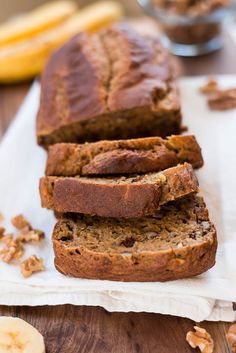 sliced loaf of banana nut bread sitting on top of a white napkin next to bananas