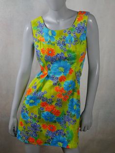 This 1970s vintage Hawaiian dress has a stunning floral pattern in blue, orange, and yellow on a green background. The sleeveless cotton summer dress has a slight scoop neckline, a relaxed-fit waistline, inverted pleats on both sides of the front, an inner back-tie so that you can fit the dress to be show your form. An 11-inch (27.94cm)zipper in the back makes dressing an ease. Size 8 US, 12 UK Bust = 36 inches (91cm) Waist = 37 inches (93.98cm), with inner tie-back if you want a more fitted look Hips = 42 inches (106.68cm) Dress Length = 35 inches (88.9cm)  Brand label: Noelani Casuals (Made in Hawaii) Material: Cotton Condition: Excellent (Professionally Cleaned ... soft and supple, with no stains, tears, wear spots, or weaknesses in the seams)   --- DESCRIPTION ASSURANCE --- I want you Hawaiian Vintage, Vintage Hawaiian Dress, Cotton Summer Dress, Vintage Tropical, Cotton Dress Summer, Hawaiian Dress, Brand Label, Vintage Hawaiian, Sleeveless Floral Dress