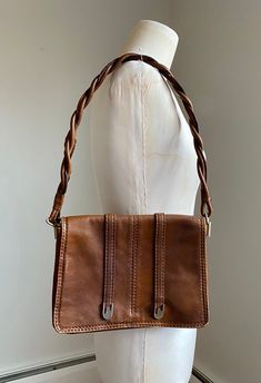 I can't get enough of this gorgeous 1970's Italian made leather shoulder bag by Mantessa. The leather outside and braided shoulder strap is a warm caramel brown color and super soft. The inside is an accordion style with a suede lining. There are three compartments and a zippered security pocket.  The purses closes with a snap and has some metal accents. The strap maintains its shapes as it is tightly twisted leather pieces.  This purse has been loved but still has a lot of life left! The corner Retro Leather Shoulder Bag, Classic Vintage Fashion Shoulder Bag, Vintage Cognac Shoulder Bag For Formal Occasions, Retro Vintage Brown Shoulder Bag For Everyday, Formal Vintage Soft Leather Shoulder Bag, Vintage Evening Shoulder Bag In Soft Leather, Vintage Soft Leather Evening Shoulder Bag, Retro Leather Bag For Vintage Fashion, Vintage Brown Leather Shoulder Bag