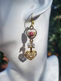 "These pretty double gold heart earrings are brand new and made by me. Two extra sparkle ball charms add a bit of shimmer to the piece. All aspects of the earrings are gold plated over alloy metal. Middle piece is rose gold plated.  Leverback attachment.  Measures just about 2\" in length. Made with love." Gold Heart-shaped Earrings With Dangling Charms, Rose Gold Heart Charm Earrings For Valentine's Day, Rose Gold Heart Charm Earrings For Mother's Day, Heart-shaped Gold Earrings With Dangling Charms, Gold Heart-shaped Flower Earrings, Rose Gold Double Heart Earrings For Mother's Day, Gold Flower Earrings For Valentine's Day Anniversary, Valentine's Day Gold Earrings With Dangling Charms, Gold Flower Earrings For Anniversary On Valentine's Day