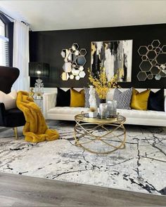 a living room with black and white furniture, gold accents and art work on the wall