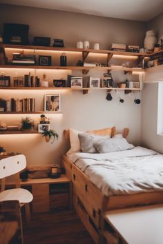 a bed sitting under a window next to a wooden shelf filled with books and other items