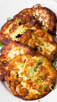 two potato patties on a white plate with green onions