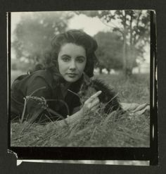 an old black and white photo of a woman laying in the grass