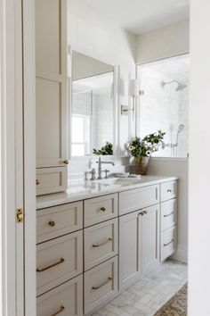 a bathroom with white cabinets and marble counter tops