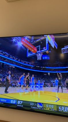 a flat screen tv mounted on the wall above a basketball court in a sports arena