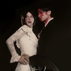 a man and woman dressed up as zombies with blood on their faces, standing next to each other