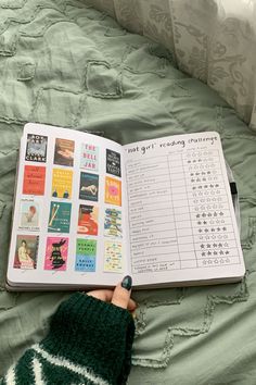 someone is reading a book on the bed with their hand in front of an open book