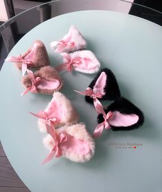 four pairs of slippers with pink bows on them sitting on top of a glass table