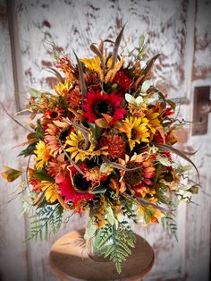 a vase filled with lots of colorful flowers on top of a wooden table next to a door