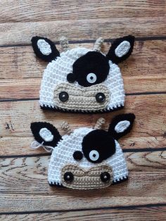 two crocheted cow hats sitting on top of a wooden floor