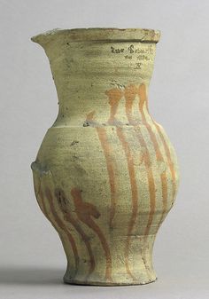 an old vase is sitting on a white surface with brown lines painted on the side