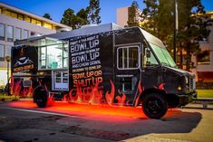 a food truck with flames painted on it's side parked in front of a building