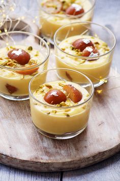 four desserts in small glass dishes on a wooden tray