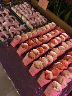 a table topped with lots of cupcakes covered in pink frosted icing