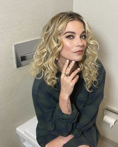 a woman sitting on top of a toilet in a bathroom