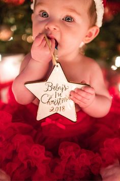 a baby wearing a santa hat and holding a star ornament