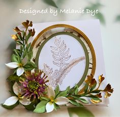 a card with flowers and leaves on it, sitting on top of a white table