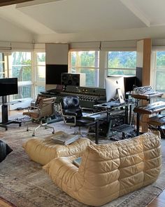 a living room filled with lots of furniture next to two large windows and a piano