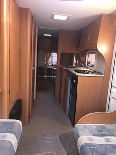 the inside of an rv with two beds and kitchenette in it, including stove top oven