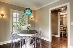 a dining room table with clear chairs and a chandelier hanging from the ceiling