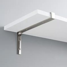 the corner of a white shelf with metal brackets