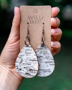 a pair of white and brown wood tear shaped earrings on a card with the tag that says wild embers