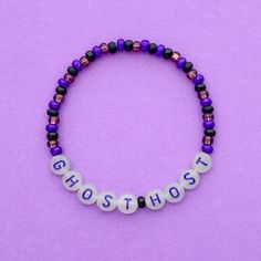 the word ghost spelled in white letters on a purple beaded bracelet with multi - colored beads