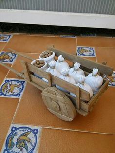 an old wooden wagon filled with white jugs sitting on top of a tiled floor