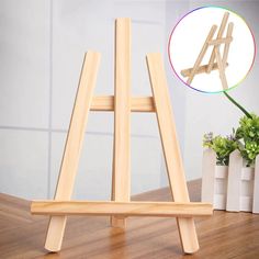 wooden easel standing on top of a table next to vases and potted plants