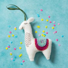 a white llama ornament on a blue background surrounded by confetti