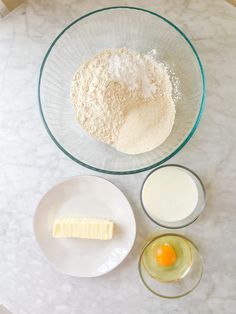 ingredients to make cake sitting on top of a white marble countertop, including butter, eggs and flour