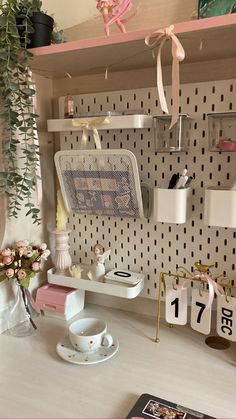 there is a desk with flowers and other items on the shelf next to it,