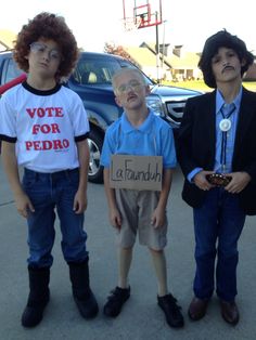 three young boys standing next to each other in front of a parking lot holding signs