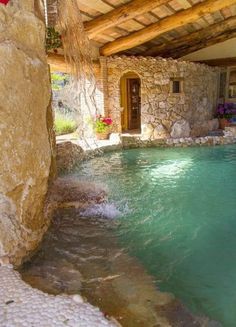 an indoor swimming pool with stone walls and steps leading up to the door that leads into it