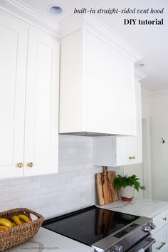 a kitchen with white cabinets and black stove top in front of a basket full of bananas