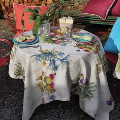 the table is set for two outside with colorful pillows and blankets on top of it