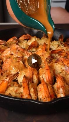 someone is pouring sauce on some food in a skillet with shrimp and bread crumbs