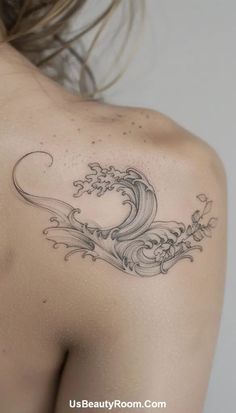 a woman's back with a wave tattoo on it