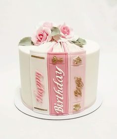 a decorated birthday cake with pink and white frosting on a plate, topped with flowers