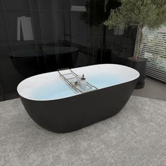 a bath tub sitting on top of a rug next to a black sink and toilet