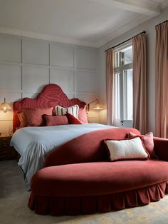 a large bed sitting next to two lamps on either side of a window in a bedroom