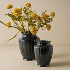 two black vases with yellow flowers in them