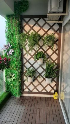 a balcony with potted plants on the wall and wood flooring in front of it