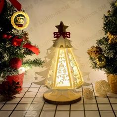 a lighted christmas tree sitting on top of a tiled floor next to two small trees