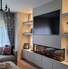 a living room with a couch, fireplace and television on the wall in front of it