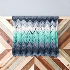 a crocheted blanket hanging on a wooden wall