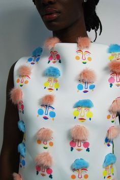 a woman in a white top with colorful pom - poms on her neck